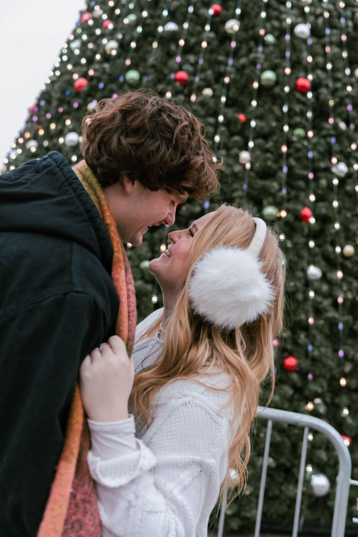 A couple laughing together beside a Christmas tree